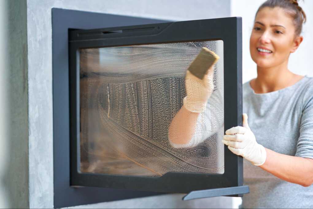 young woman cleaning a fireplace door