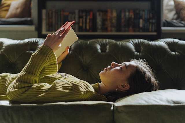 Person reading a book on a couch